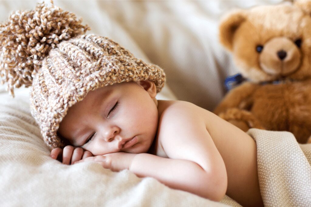 Bébé qui dort avec un bonnet et peluche