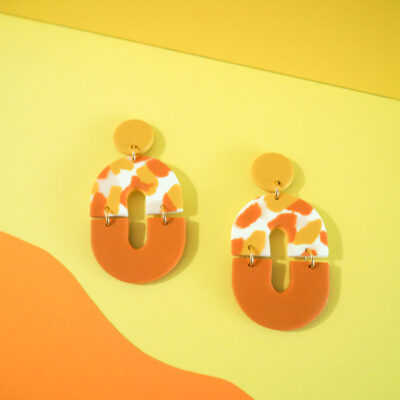 Boucles d'oreilles ovales avec une partie motif terrazzo blanc, rose, jaune et orange et une partie unie orange