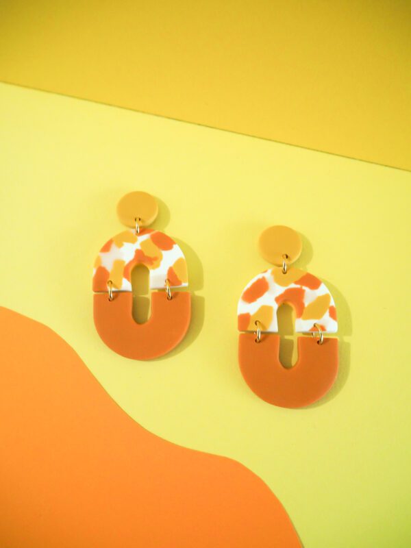 Boucles d'oreilles ovales avec une partie motif terrazzo blanc, rose, jaune et orange et une partie unie orange