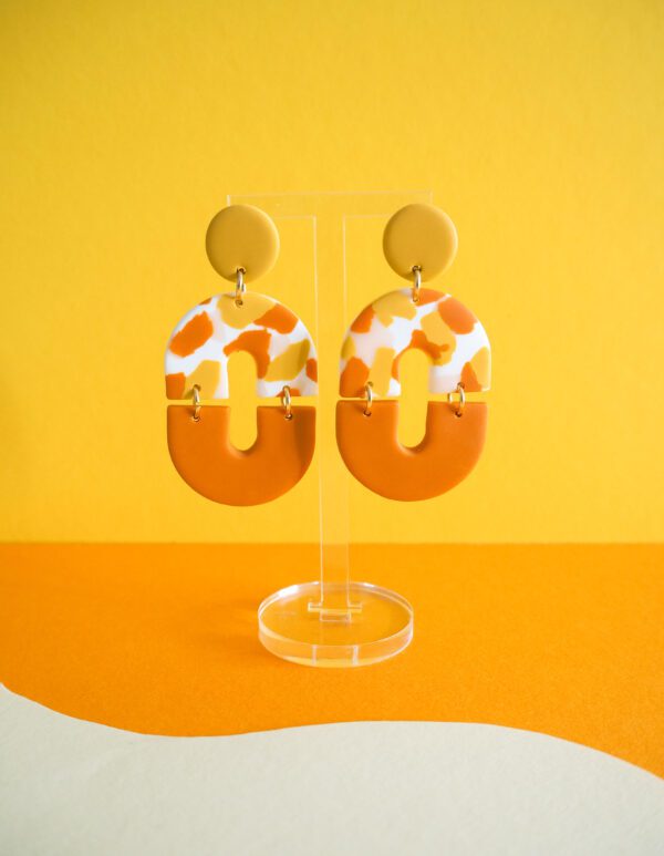 Boucles d'oreilles ovales avec une partie motif terrazzo blanc, rose, jaune et orange et une partie unie orange