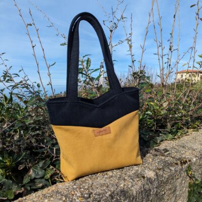 petit sac en tissu jaune et noir posé sur un muret