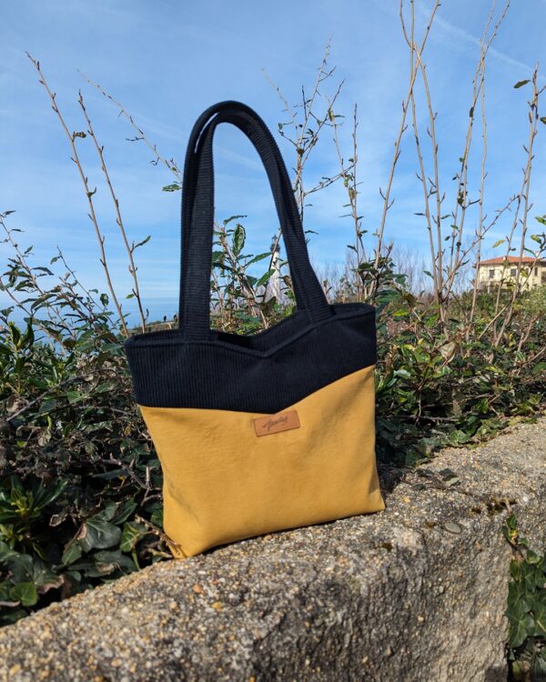 petit sac en tissu jaune et noir posé sur un muret