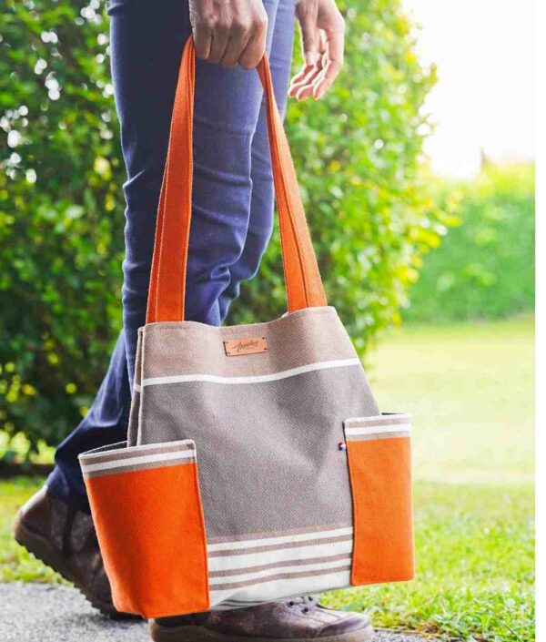 Sac toile basque orange et taupe, porté à la main