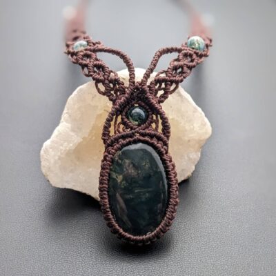 collier macramé agate mousse en gros plan devant une géode quartz