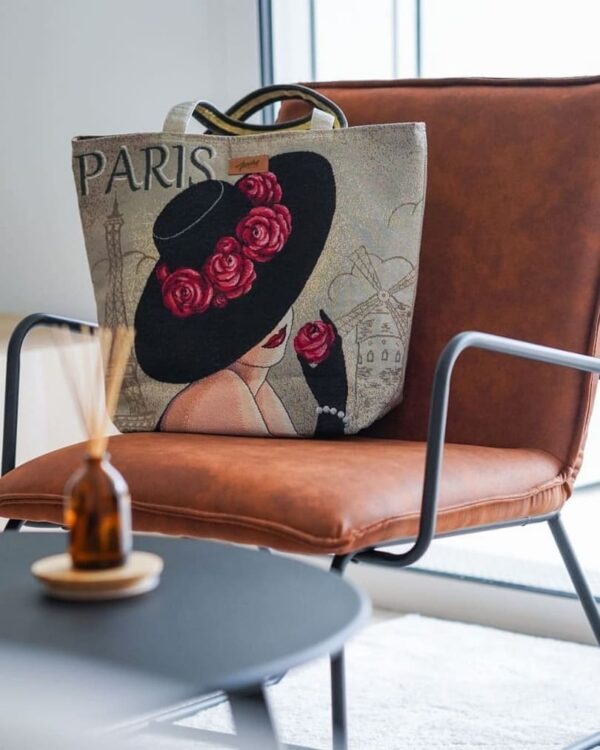 Tote bag artisanal avec motif jacquard Paris, avecune femme en chapeau noir orné de roses rouge posé sur un fauteuil en cuir marron