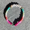 Bracelet minimaliste en perles de rocaille avec mot "bisou" dégradé allant du rose au bleu. Perles avec écriture dorée et fermoir ajustable.