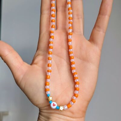 Collier ras de cou mignon tons orange et rose pastel. Perles étoiles et coeur.
