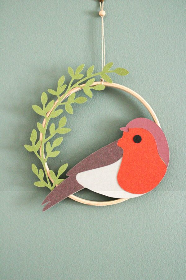Décoration murale faite main avec oiseau en papier et feuillages dans un cercle en bois