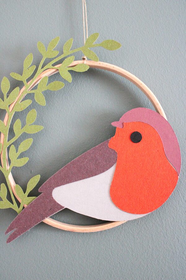 Cercle mural en bois avec oiseau en papier et détails végétaux