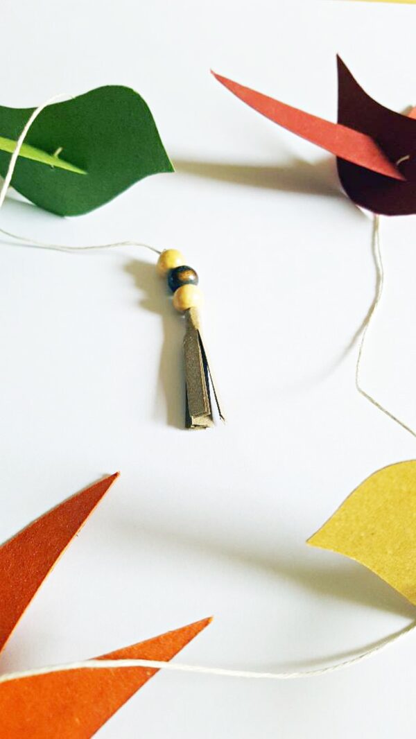 Guirlande artisanale de cinq oiseaux en papier recyclé coloré, montée à la main sur un fil avec perles de bois et clochette décorative. Idéale pour chambre d’enfant, décoration poétique ou fête nature.