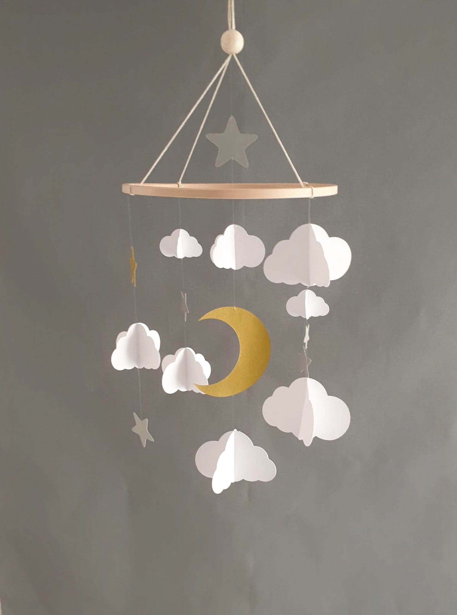 Suspension décorative en papier sur le thème du ciel étoilé, avec une lune dorée et des nuages légers.