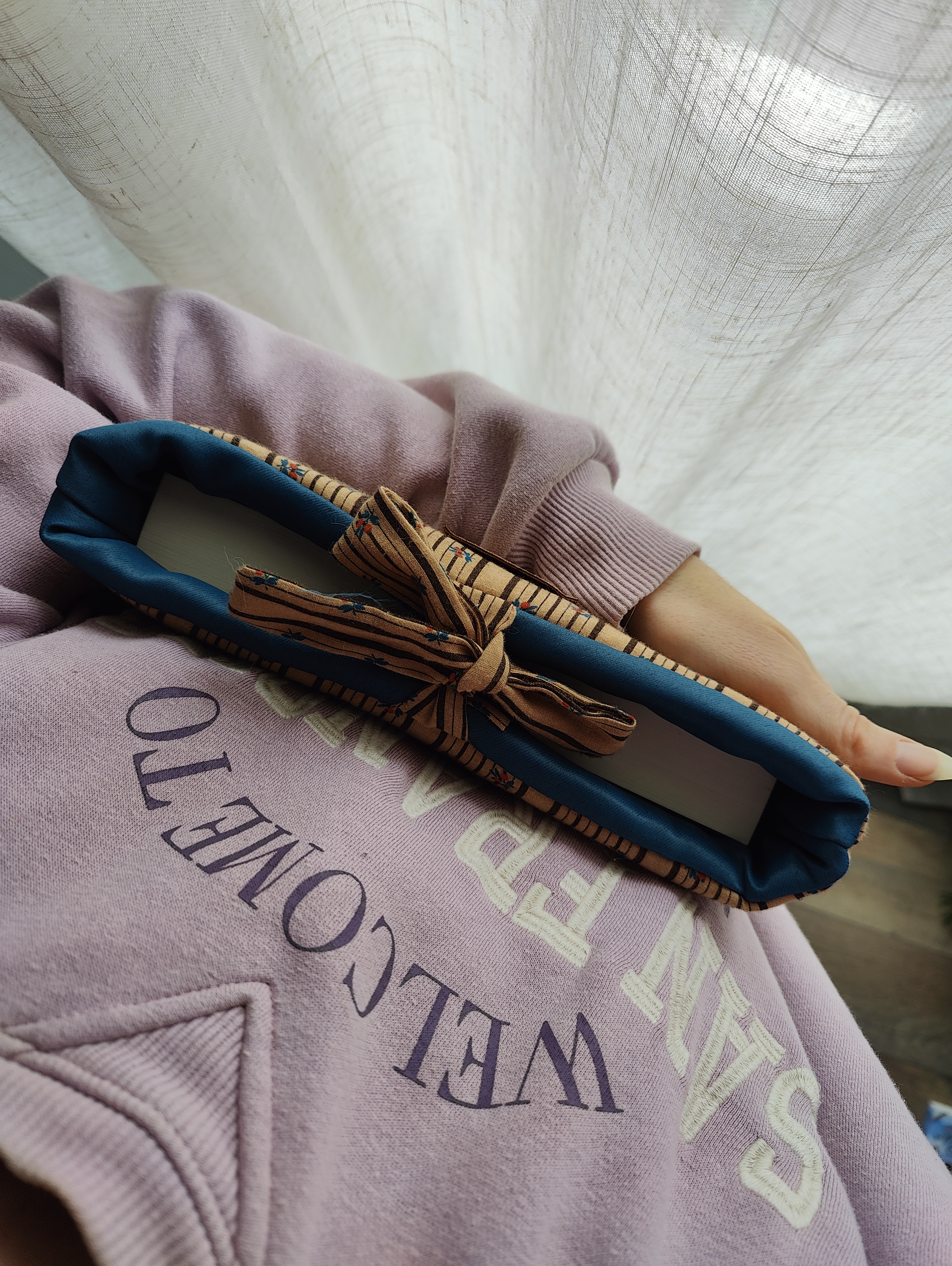 Pochette livre poche fermée avec lien à nouer, tenue dans les bras.
