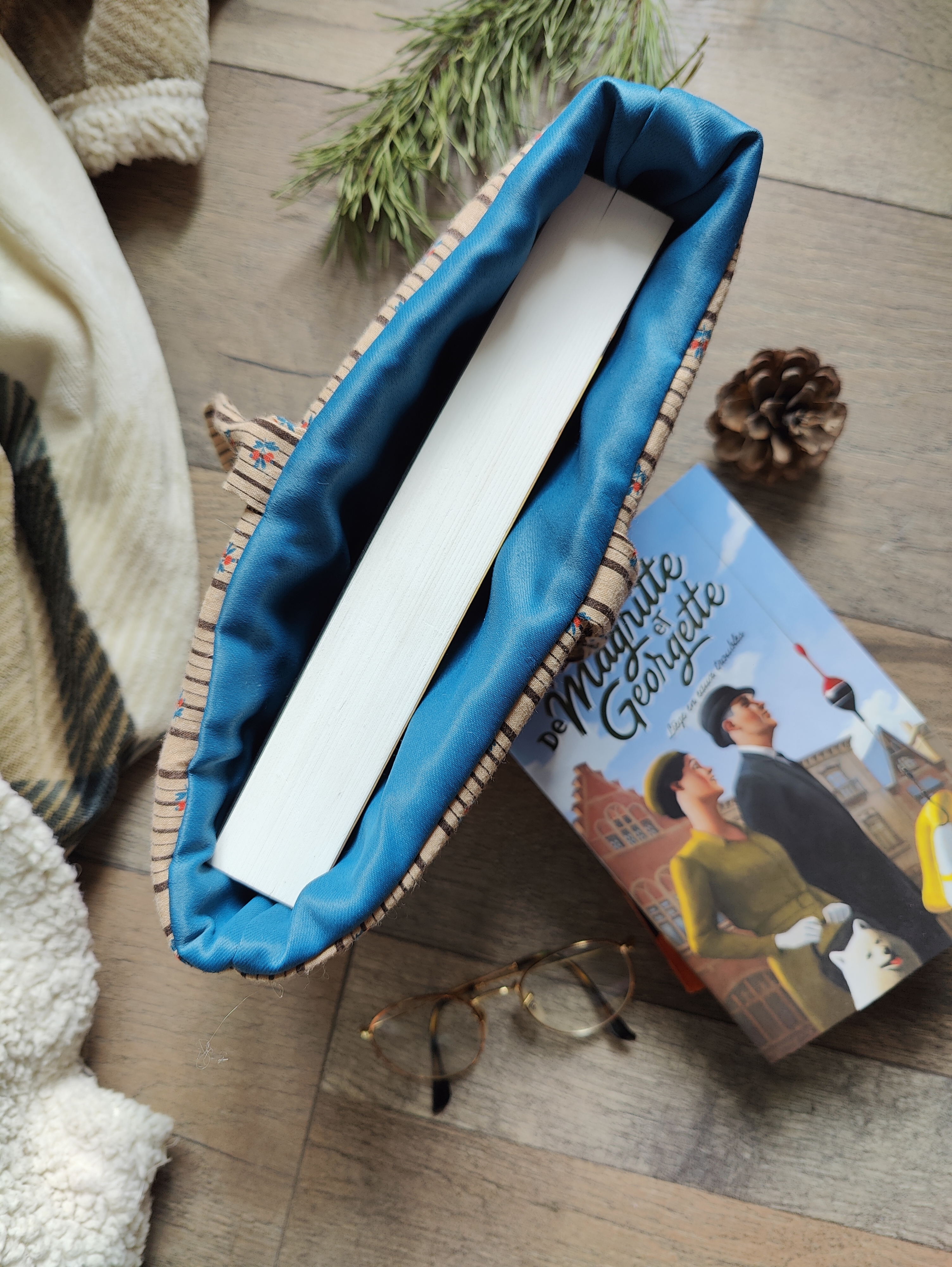 Vue intérieure d’une pochette pour livre avec doublure turquoise et livre glissé à l’intérieur.