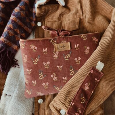 Pochette à livre en velours milleraies fleuri posée sur une veste en velours côtelé, avec une écharpe. Style chaleureux et automnal.