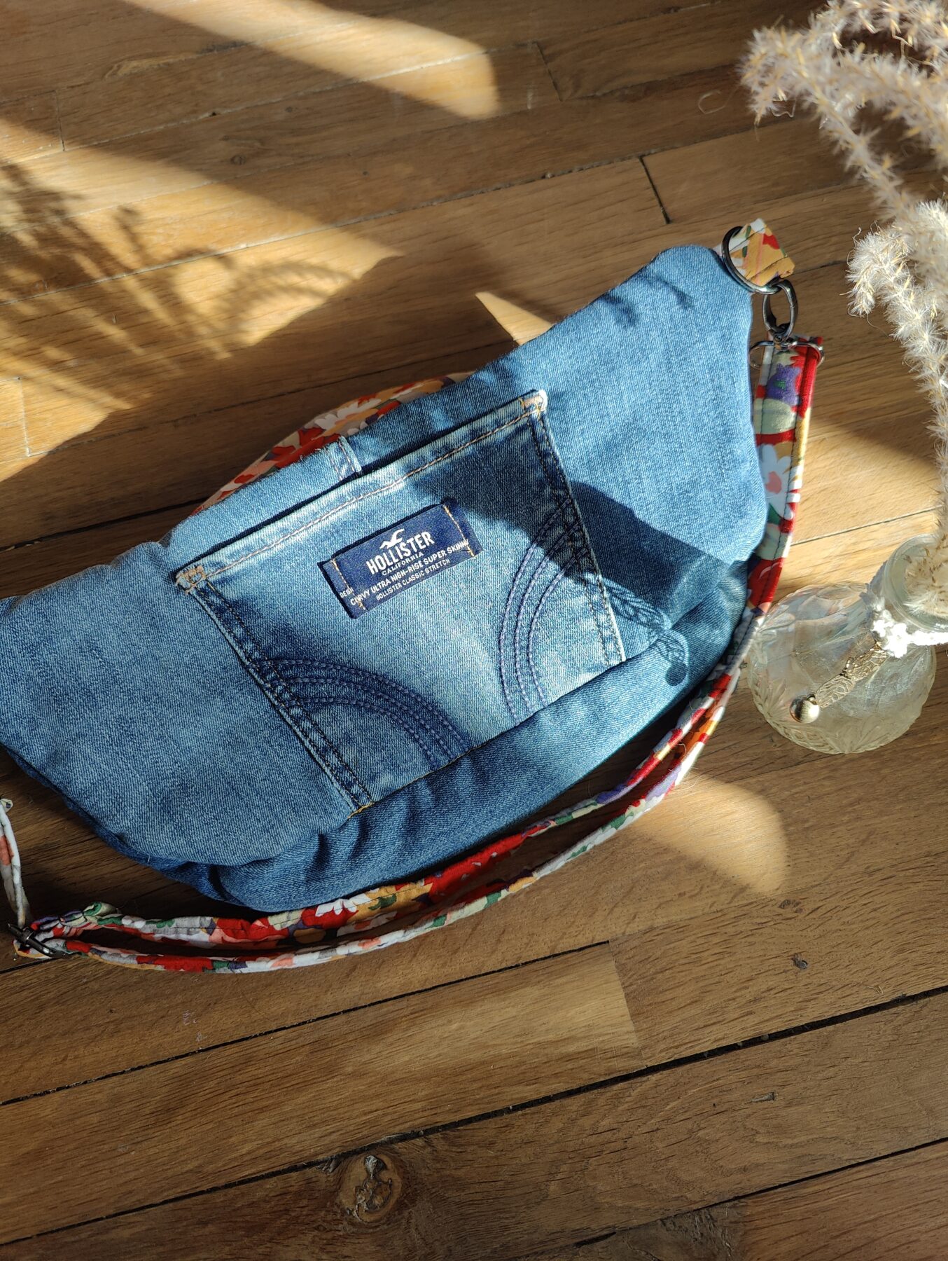 Sac banane upcyclé jean bleu. Intérieur fleuri "Bouquet d'Antan". Poche arrière jean cousue au dos avec étiquette Hollister