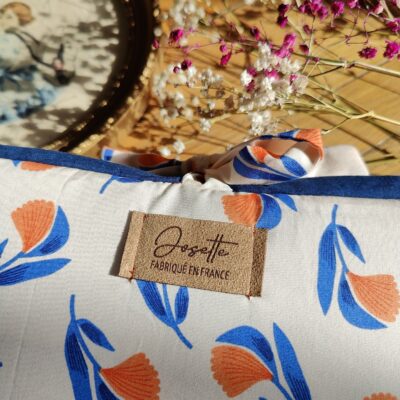 Détail du tissu upcyclé de la pochette, motif fleurs orange et bleu sur fond clair.