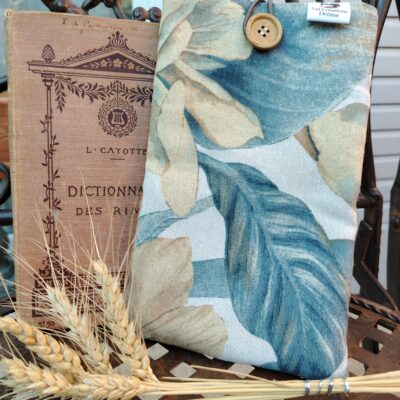 housse addossé à une chiase posé à coté d'un livre ancien posé également sur une chaise en fer forgé.