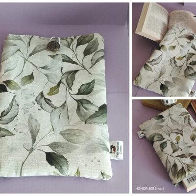 Un collage de trois photos présentant une pochette de livre en tissu fait main, ornée d'un motif de feuilles vert sauge sur fond beige. La pochette est illustrée sous plusieurs angles, montrant son utilisation pour protéger un livre de poche, ainsi que son bouton de fermeture stylé, son élastique et son étiquette de marque.