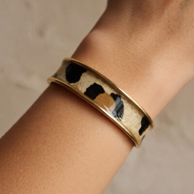 Manchette dorée au motif léopard chic portée au poignet, bijou artisanal femme tendance wild chic.