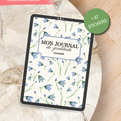 Couverture du journal de gratitude mensuel avec un fond floral bleu et vert, et un badge vert '+47 stickers', posé sur une table en bois