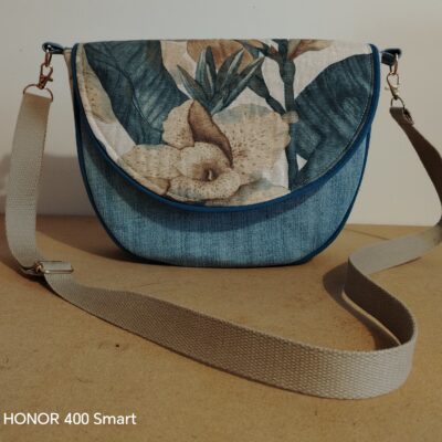 "Sac besace artisanal en tissu denim bleu et rabat à motif floral exotique, avec une bandoulière réglable en coton beige, créé par Val Créations Drôme."