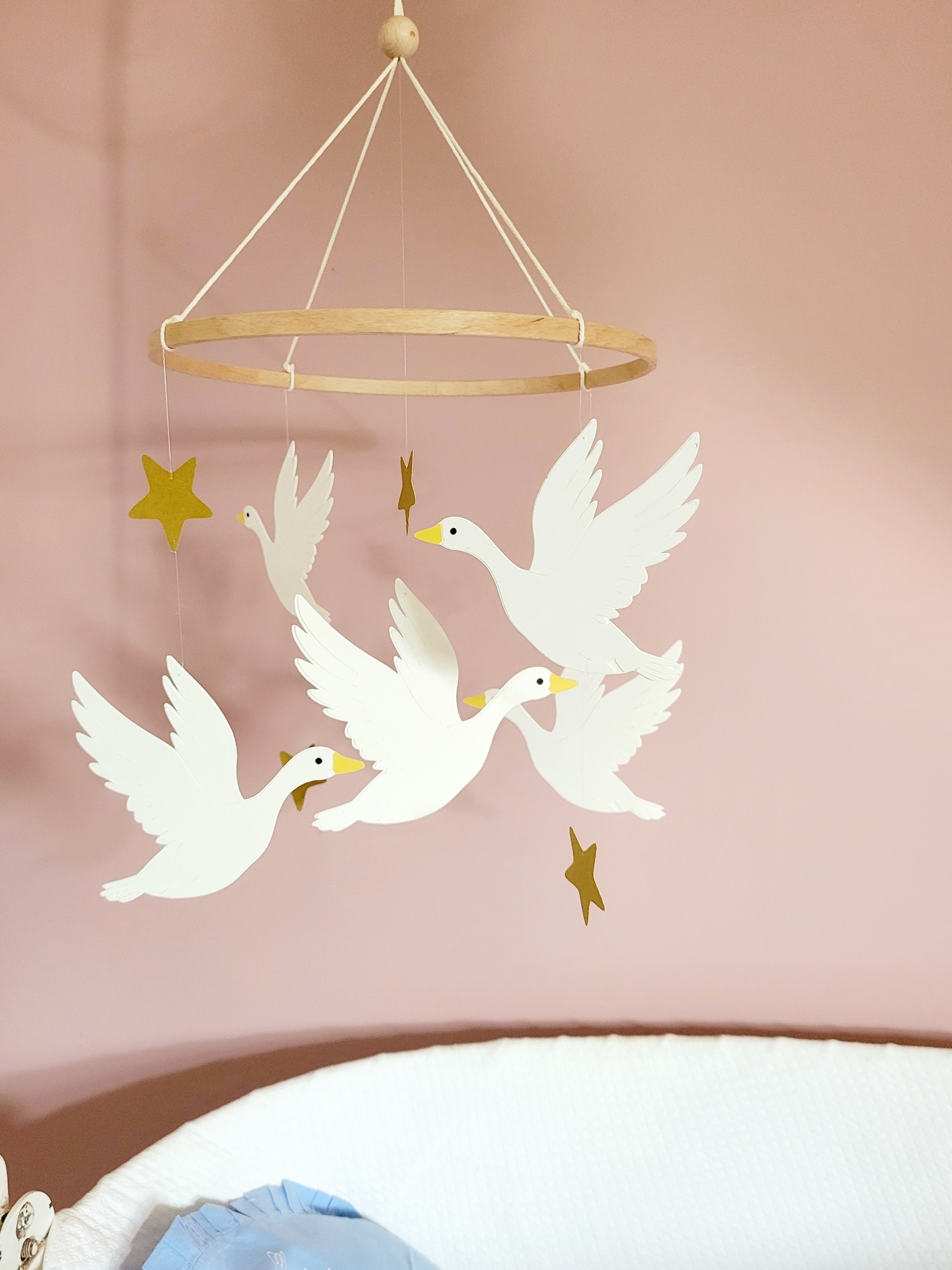 Mobile poétique pour nouveau-né composé de silhouettes d'oies en papier et d'étoiles jaunes.