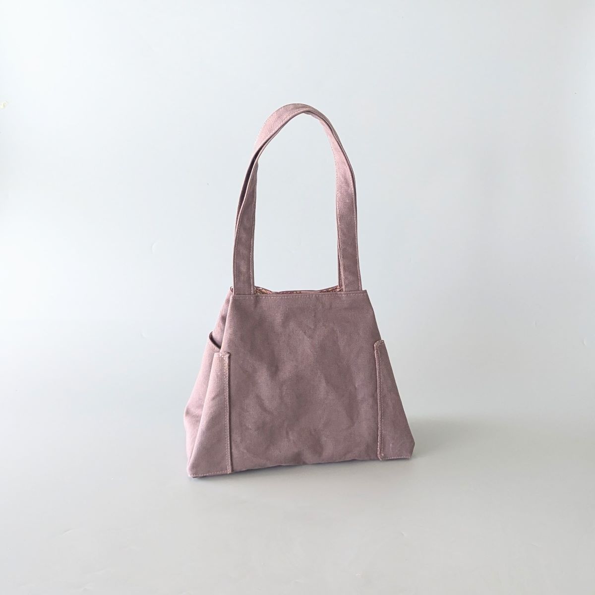 Le sac trapèze Enara prune , les poches latérales rentrées.
