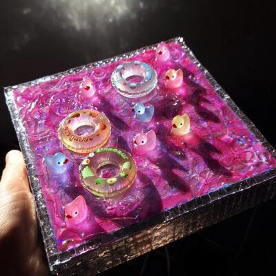 Tableau décoratif 3D fait main représentant une piscine avec de l'eau rose et des bouées.