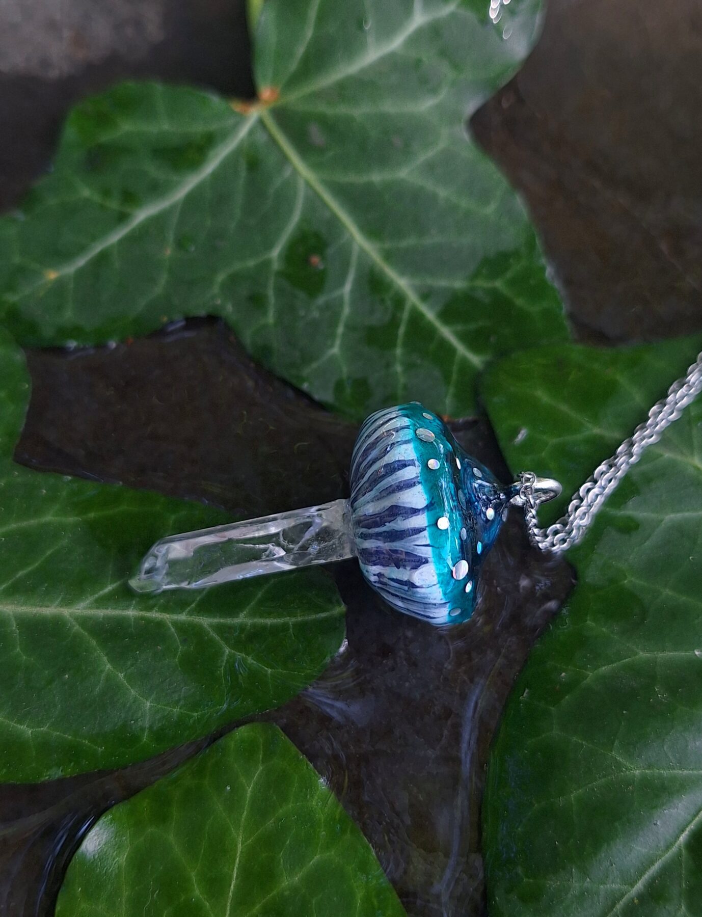 Pendentif en forme de champignon avec pied en cristal de roche naturel. Pendentif 3x5 cm, chaîne 45 cm. Quartz naturel, pâte polymère, résine d'époxy. Bleu vert, bleu lagon, bleu canard, transparent. Soigneusement emballé dans une boîte cadeau prête à offrir. Fluorescent réactif à la lumière UV néon, phosphorescent lumineux dans le noir. Féerique, forêt, cottagecore, fairycore, boho, psychédélique, witchy, kawaii, mignon, fantastique, champêtre.